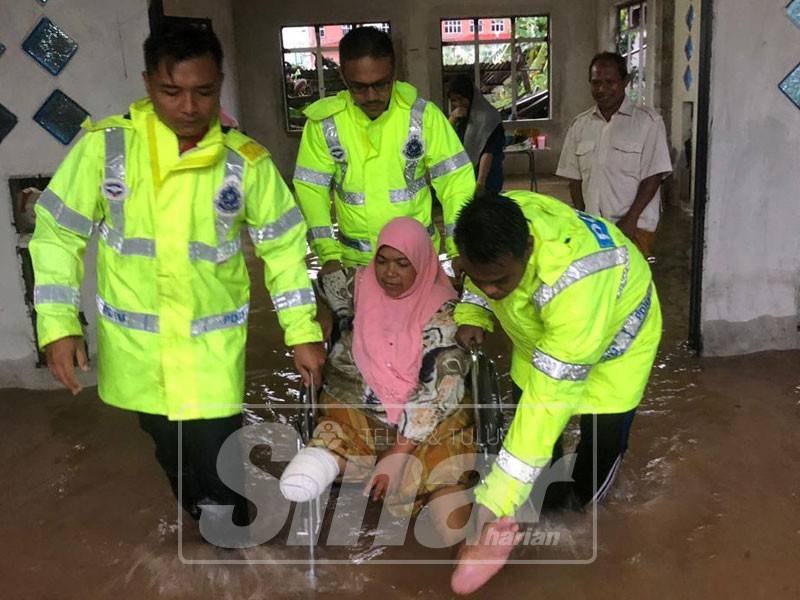 Ramli (belakang) dan isterinya Fatimah dibantu anggota polis dibawa keluar dari rumah mereka di Kampung Kijing pagi tadi.