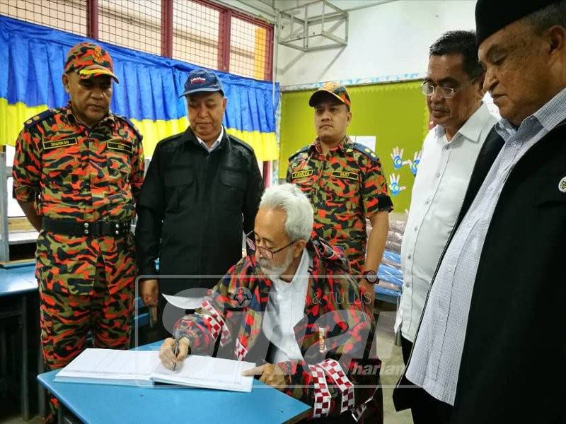 Raja Kamarul Bahrin mengisi rekod buku pelawat ketika melawat ke pusat pemindahan banjir di SK Marang.