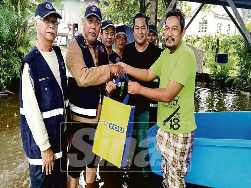 Mohd Hanafiah (dua, kiri) menyampaikan barangan makanan kepada mangsa banjir. 