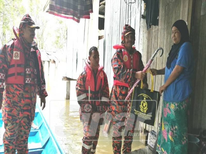 Suhaimi (dua,kanan) menyampaikan sumbangan makanan kepada salah seorang penduduk semasa program 'Door to Door' di Kampung Kubang Pak Itam.