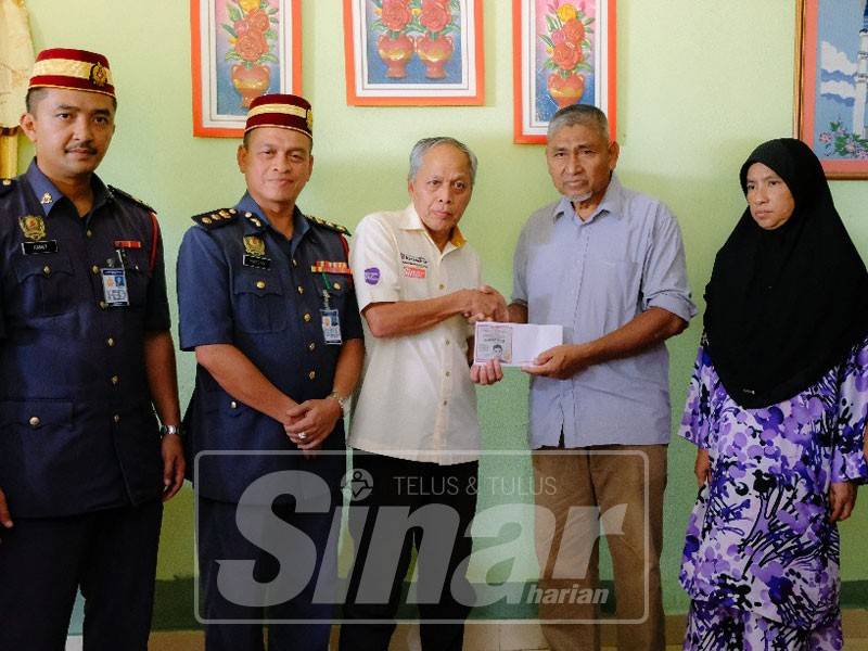 Muhammad Nasir (tiga,kiri ) menyampaikan cek kepada Mohd Kassim Abd Hamid di kediaman mereka di sini, hari ini.
