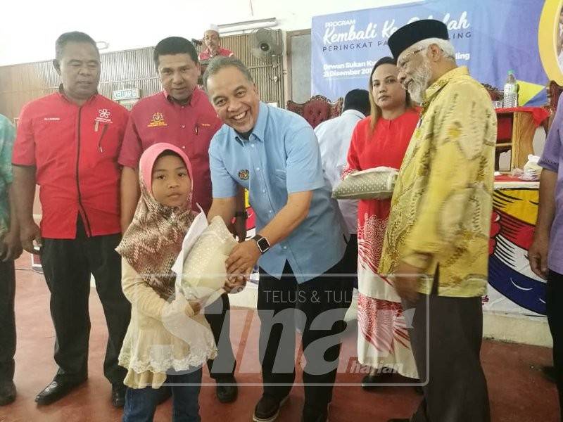 Amiruddin menyampaikan sumbangan kepada salah seorang murid.
