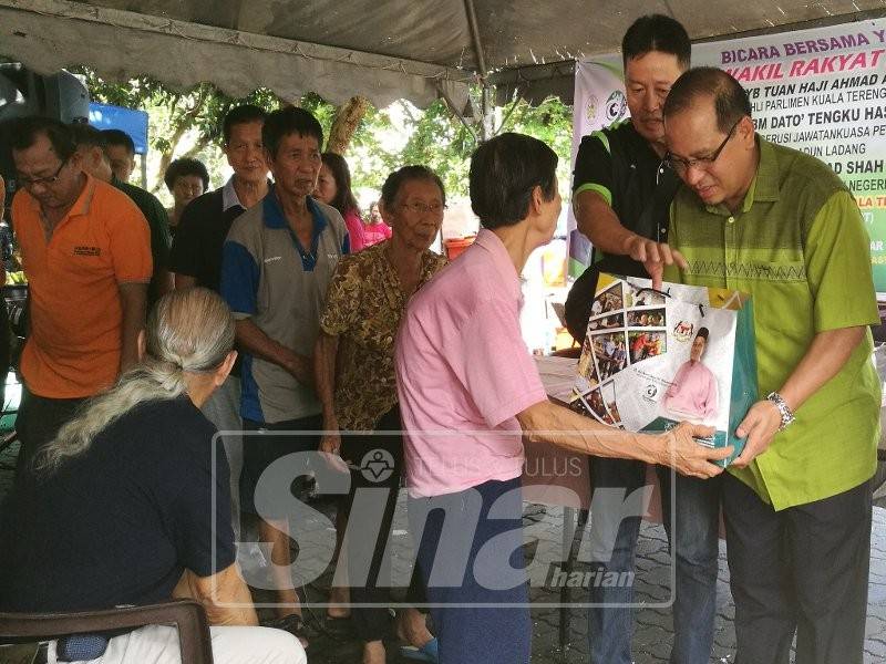 Ahmad Amzad (kanan) menyampaikan sumbangan kepada warga emas selepas selesai Bicara Bersama Yang Berhormat Wakil-Wakil Rakyat Kuala Terengganu di Pasar Pagi Kampung Tiong.