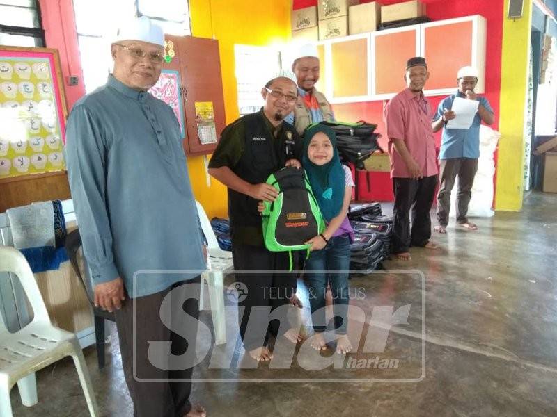 Najmi (hadapan) bersama wakil Geng Talaqi menyampaikan sumbangan hasil bantuan orang ramai kepada murid sekolah.