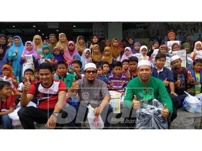 Rosli (tengah) bersama penerima di Majlis Back To School, di sebuah pasaraya, hari ini.