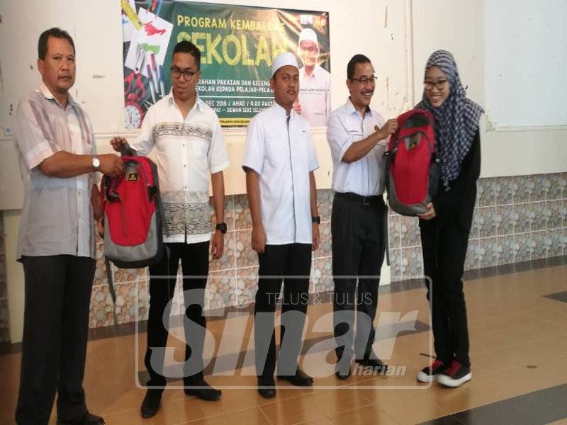 Dr Noor Azmi(dua kanan) turut berkesempatan menyerahkan sumbangan set kelengkapan sekolah kepada sebahagian pelajar memerlukan Dun Selinsing sambil diiringi Ahmad Saqif Ansorullah (tiga kiri).