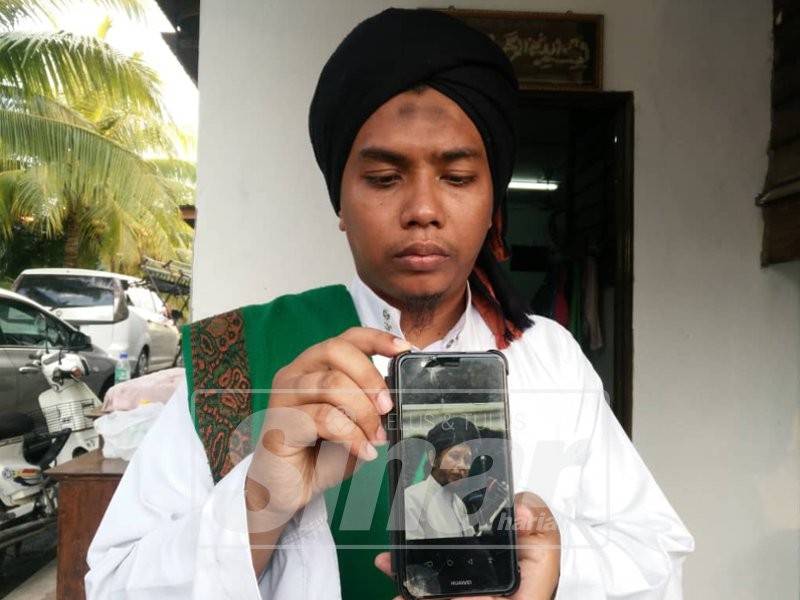 Mohd Firdaus menunjukkan gambar ayahnya yang disimpan dalam telefon bimbitnya.