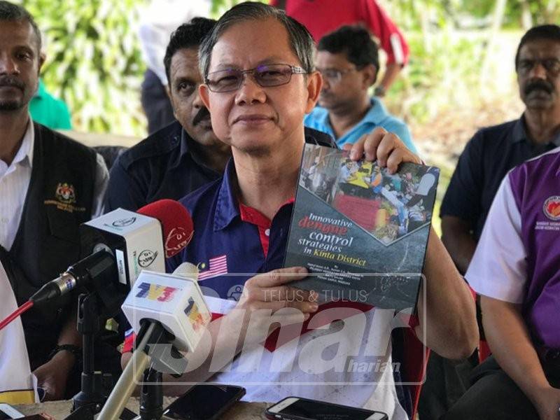 Boon Chye menunjukkan buku yang menunjukkan kaedah-kaedah pengawalan denggi yang berkesan di sekitar rumah selepas merasmikan program Gotong Royong dan Kesedaran Denggi di Kampung Rapat Jaya Tambahan, hari ini.