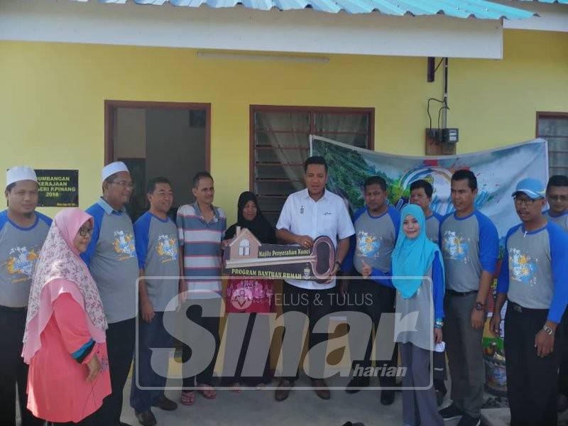 Norizan menerima replika kunci daripada Dr Afif (tengah) sebagai simbolik penyerahan bantuan rumah selepas keluarga mereka ditimpa musibah banjir tahun lalu.