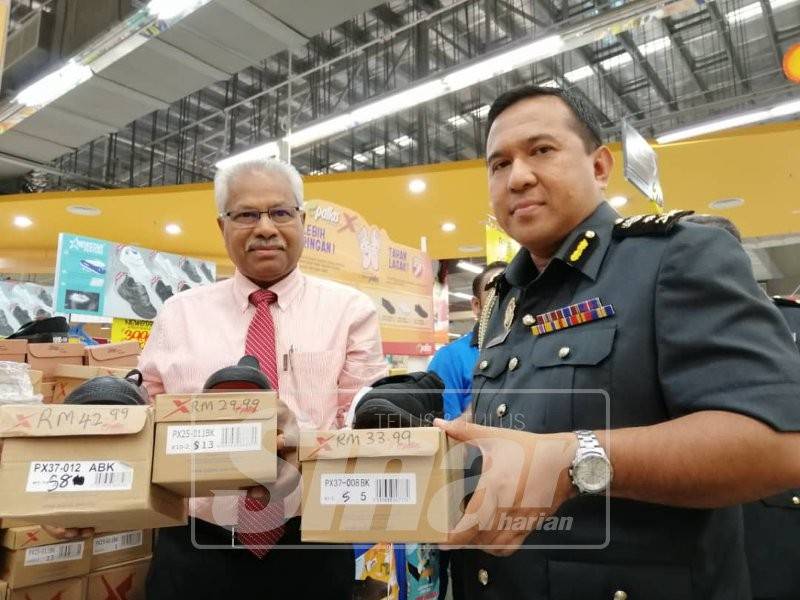 Sivanesan dan Shamsul Nizam menunjukkan perbezaan harga kasut sekolah hitam sempena pemeriksaan barangan keperluan sekolah di Pasar Raya Mydin Meru, hari ini.