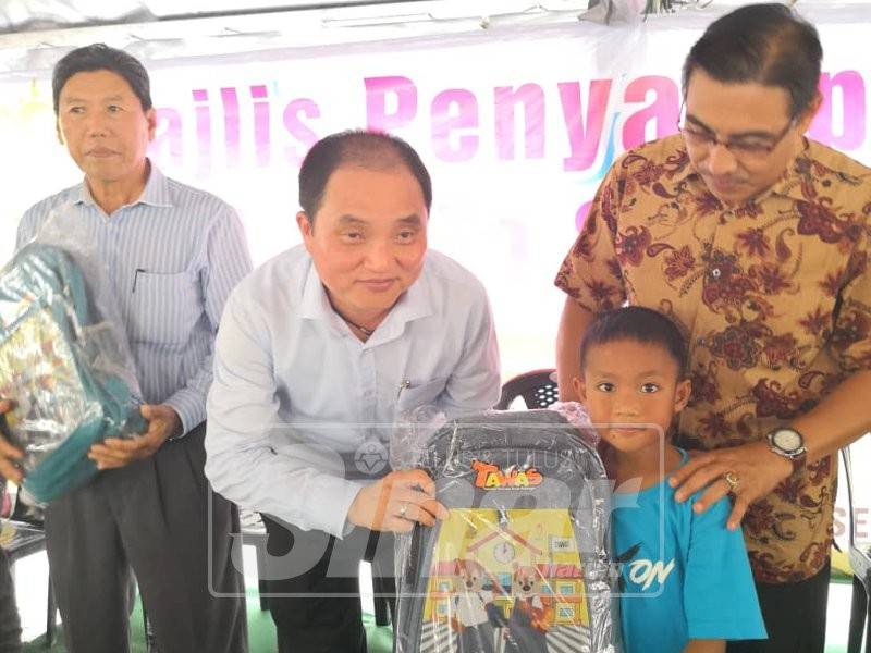 Suee Lim (dua kiri) bersama Muslimin (kanan) menyampaikan beg sekolah kepada salah seorang penerima pada Program Back to School di pekarangan Pejabat Dun Sekinchan, di sini.