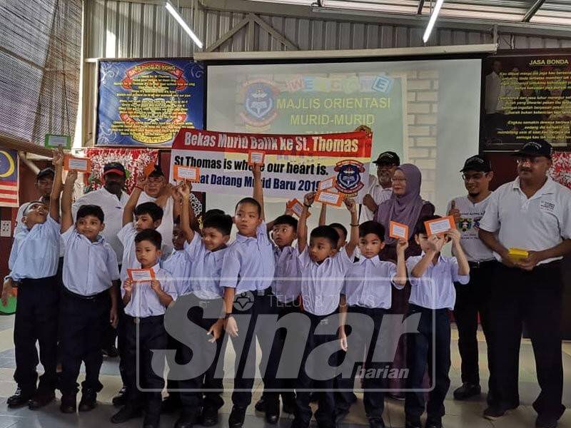 Abdul Rahman (dua, kanan) bersama pelajar yang menerima bantuan pada Program Bekas Murid Balik Ke St Thomas di Majlis Orientasi Murid Tahun 1 2019 di SK St Thomas di sini hari ini.