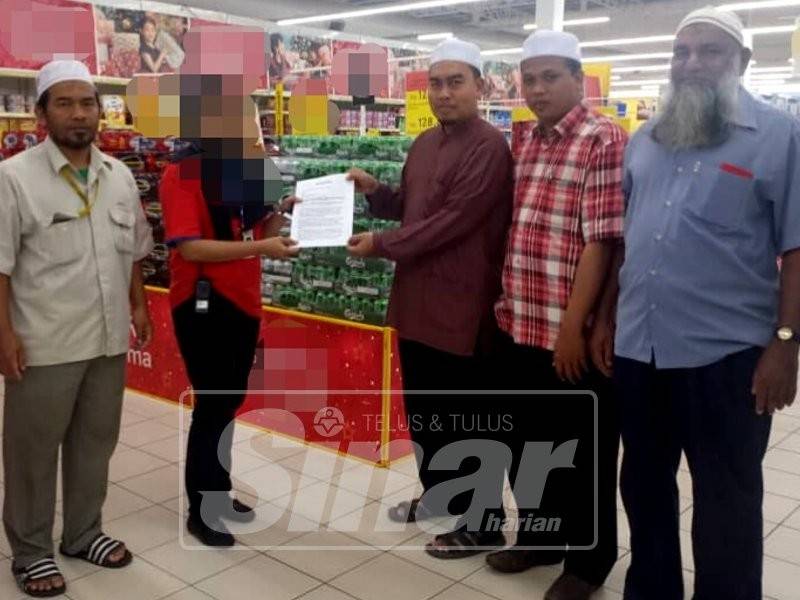 Ahmad Fadzli (tiga, kanan) menyerahkan memorandum bantahan penjualan minuman keras secara terbuka di sebuah pasar raya.