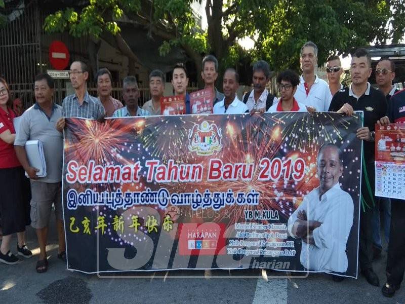 Kula Segaran (tujuh, kanan) bersama orang ramai bergambar ketika mengedarkan kalendar di Pasar Kampung Tawas, di sini.