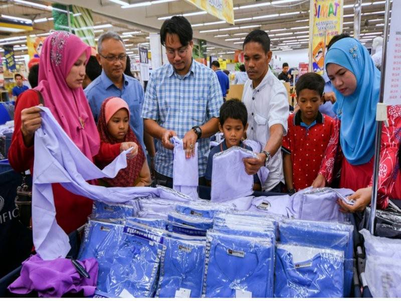 Setiausaha Akhbar Menteri Kementerian Perdagangan Dalam Negeri dan Hal Ehwal Pengguna (KPDNHEP), Mohamad Hisomuddin Bakar (empat, kiri) bersama murid daripada keluarga kurang berkemampuan memilih pakain sekolah pada Majlis Pelancaran Program Pengguna Bijak Kembali ke Sekolah di sebuah pasar raya, hari ini. Turut sama Pengarah KPDNHEP Kelantan, Khalid Tik (tiga kiri). - Foto Bernama
