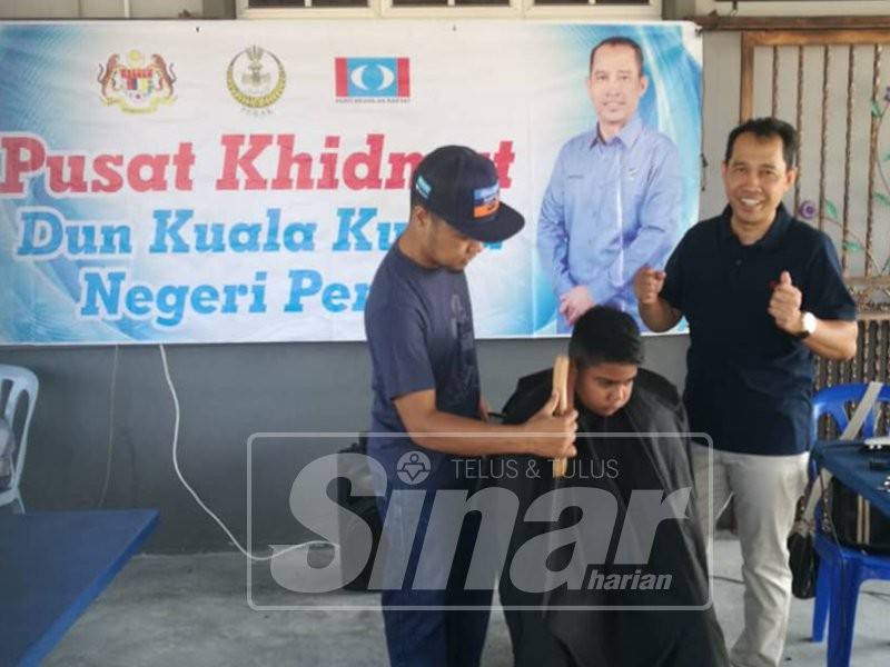 Abdul Yunus (kanan) menyantuni beberapa kanak-kanak yang mendapatkan khidmat gunting rambut percuma ditawarkan pihaknya di Pejabat Pusat Khidmat Adun Kuala Kurau di sini, hari ini.