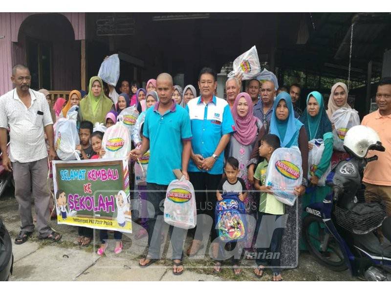 Ismail (tengah) bersama sebahagian penerima Bantuan Kembali Ke Sekolah yang ditemani ibu bapa masing-masing di hadapan Pejabat PKR Cabang Pasir Puteh.