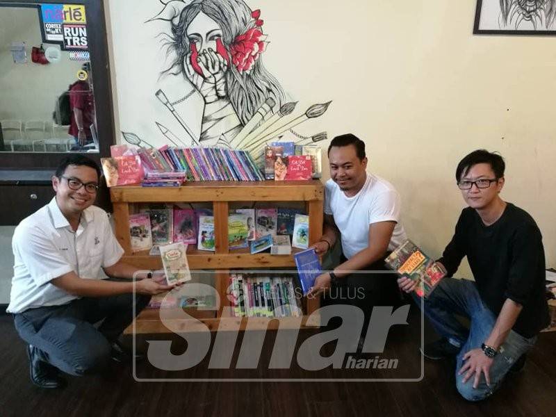 Chean Chung(kiri) bersama Penyelaras Projek #KUBE, Pang Shee Lim (kanan) dan pemilik Gunteng Barbershop menunjukkan rak buku yang dilancarkan, hari ini.
