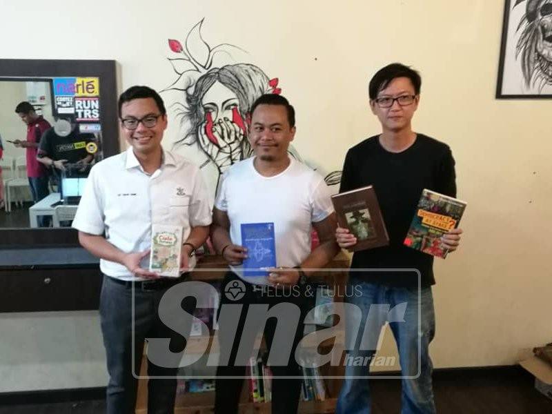 Chean Chung (kiri) bersama Shee Lim (kanan) dan Hariz menunjukkan buku yang disediakan di Gunteng Barbershop Indera Mahkota.
