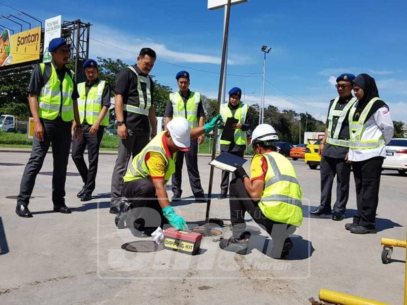 Mohd Ridzuan (tiga, kiri) melihat pemeriksaan bekalan petrol dan diesel oleh kakitangan sebuah stesen minyak, hari ini.
