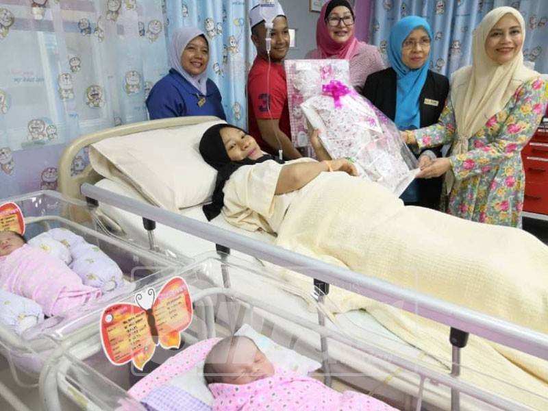 Dr Zanariah (kanan) menyampaikan cenderamata kepada Nur Aqilah yang selamat melahirkan bayi kembar tahun baru.