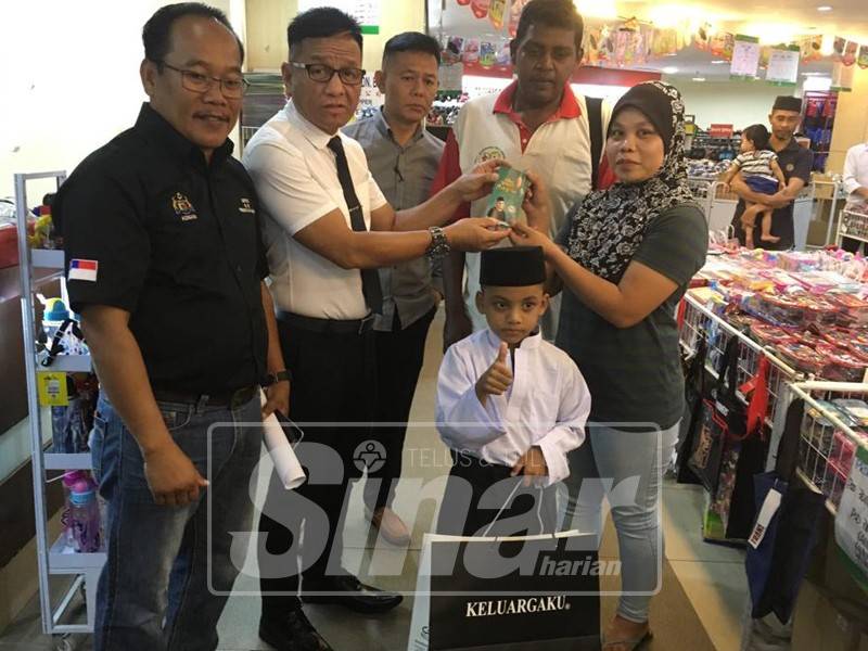 Norhizam membantu Muhammad Firas Darwisy mencuba pakaian seragam baharu sekolah agama di sebuah pusat beli belah di Bukit Baru bersama bapa, Azrin Mohd dan ibunya, Nur Aminah Pariyatna, 27.