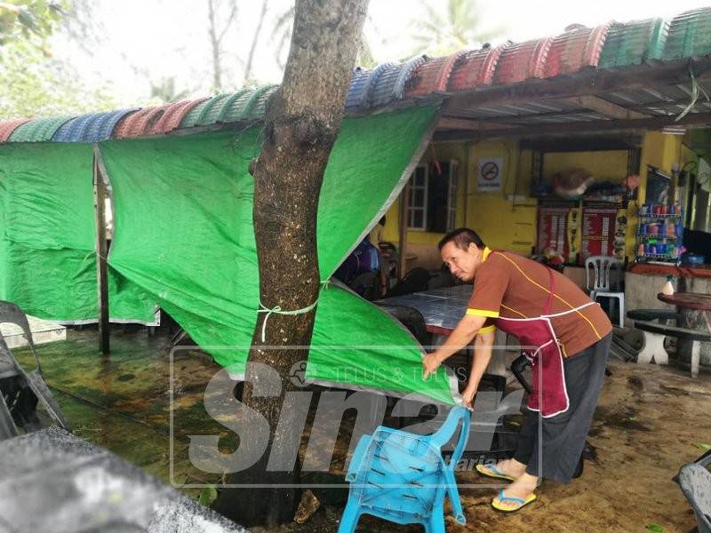 Abdul Rahman memasang tabir menggunakan kanopi untuk mengelakkan angin daripada menerbangkan pinggan mangkuk di gerainya.