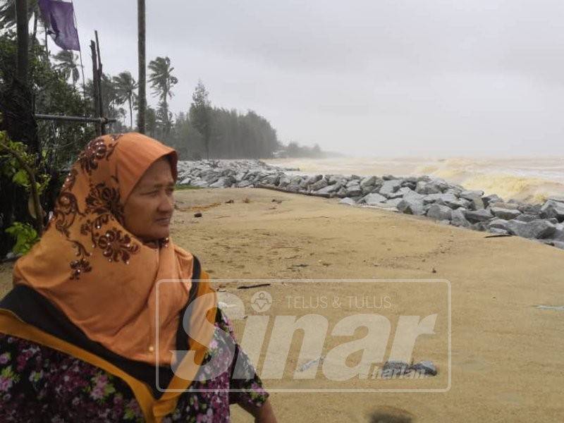 Mek Jah meninjau keadaan ombak besar di belakang rumahnya.