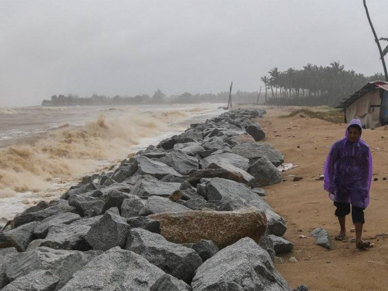 Penduduk tempatan meninjau keadaan ombak dan laut yang bergelora di benteng pemecah ombak berhampiran kediaman di Pantai Pulau Kundur. - Foto Bernama