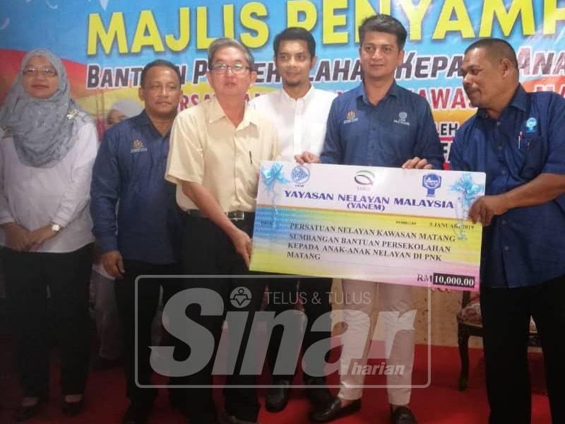 Muhammad Faiz (tengah) menyerahkan cek replika sumbangan bantuan persekolahan kepada anak-anak nelayan dari PNK Matang bernilai RM10,000 kepada wakil PNK Matang hari ini.