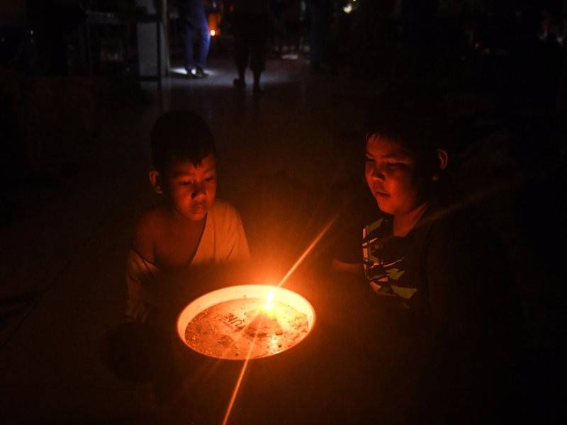 Dua kanak-kanak di pusat pemindahan duduk berteman cahaya lilin susulan ribut tropika Prabuk yang melanda wilayah selatan Thailand, Nakhon Si Thammarat. - FOTO AFP