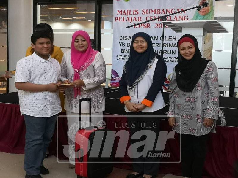 Zuhuraina (dua, kiri) menyampaikan sumbangan kepada pelajar cemerlang UPSR 2018 di kawasan Parlimen Titiwangsa.