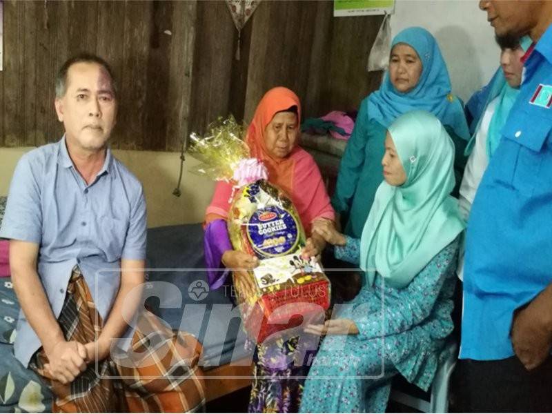 Sharifah Norhayati (kanan) menyampaikan sumbangan kepada penduduk kurang bernasib baik sempena Program Ziarah Kasih di Kampung Buluh, Kuala Berang, semalam. 