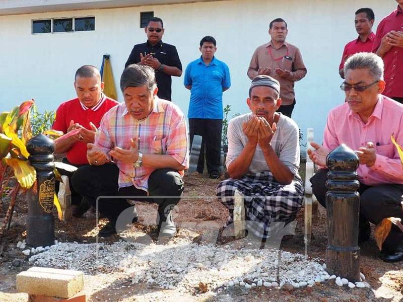 Mohamad (dua, kanan) membaca doa di pusara Muhammad Adib selepas menziarahi keluarga Allahyarham.