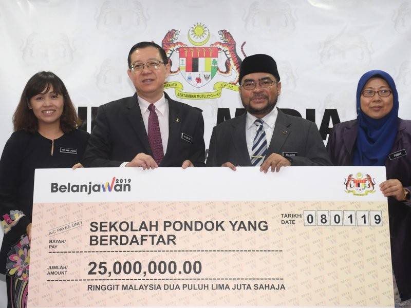 Menteri Kewangan Lim Guan Eng (dua, kiri) menyerahkan peruntukan kepada Menteri di Jabatan Perdana Menteri, Datuk Seri Mujahid Yusof Rawa pada Majlis Penyerahan Cek Kepada Sekolah Pondok Berdaftar di Kementerian Kewangan hari ini. - Foto Bernama