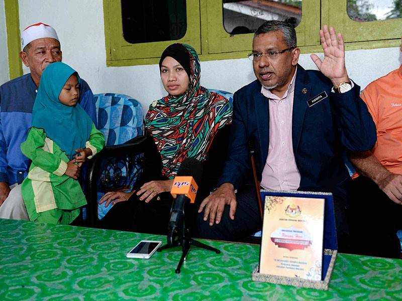 Timbalan Menteri di Jabatan Perdana Menteri Mohamed Hanipa Maidin (dua, kanan) bercakap kepada media selepas menyampaikan Anugerah Unsung Hero kepada Nazihah Hamid, 38 (dua, kanan) di kediamannya di Kampung Sungai Tembak, Parit Panjang hari ini. - Foto Bernama