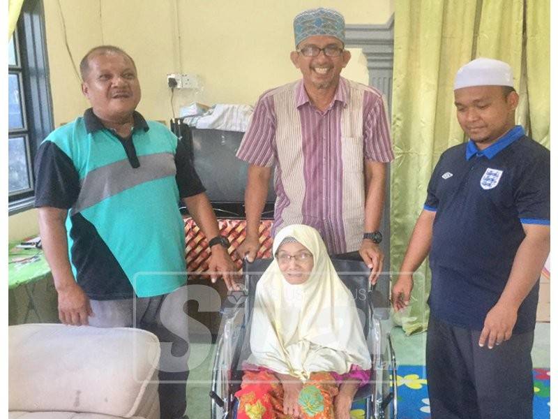 Azhar (tengah) menyampaikan sumbangan kerusi roda kepada warga emas, Che Yah Hasan di rumahnya di Kampung Tempayan Pecah, dalam PDM Gandai.