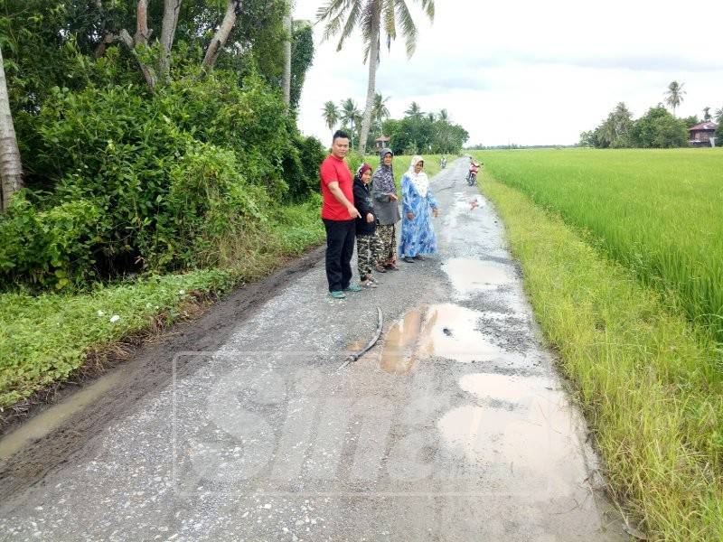 Penduduk menunjukkan keadaan jalan yang berlubang sehingga menyebabkan kebocoran paip air di kampung mereka.