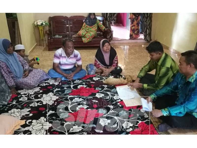 Awang (kanan) berbincang bersama keluarga mangsa mengenai pembinaan rumah berkenaan.