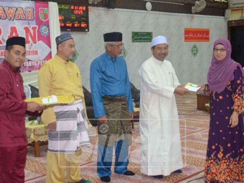 Mohd Nassuruddin menyampaikan hadiah kepada Sa'adah pada Majlis Tilawah Al-Quran Peringkat Jajahan Machang, di sini, hari ini.