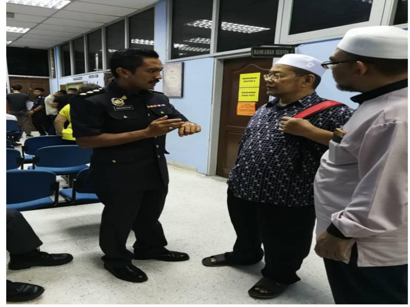 Hishamudin (kiri) memperkatakan sesuatu kepada Aziz selepas dia membayar denda terhadap hukuman yang dikenakan oleh mahkamah. Foto ihsan KPDNHEP