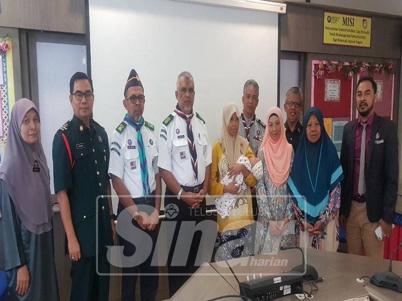 Shafruddin (empat, kiri) diringi Idris (belakang, tiga, kanan) dan Pengetua Cemerlang SMK Bukit Kuang, Wan Mohd Salleh Wan Ismail (belakang, dua, kanan) menyampaikan kepada Nur Hazwani.
