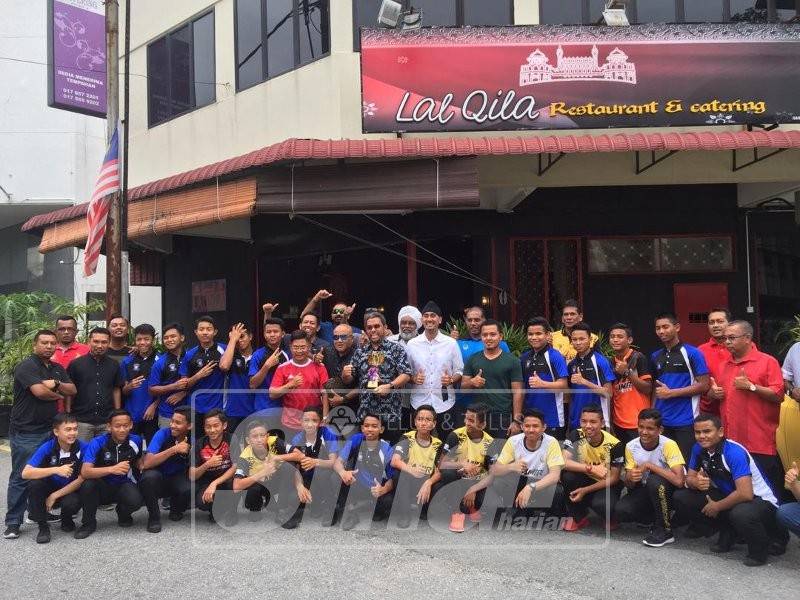 Azhar (berdiri, tengah) memegang piala dan bergambar bersama pengurus dan pasukan hoki Perak bawah 14 dan 16 tahun.