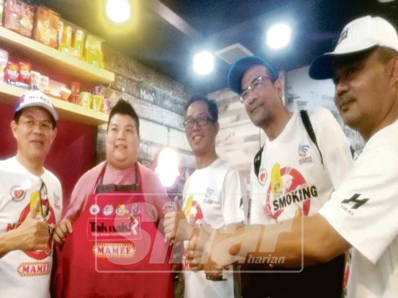 Chee Leong (tengah) menyampaikan apron kepada pengusaha makanan ketika walkabout di Jonker Walk.