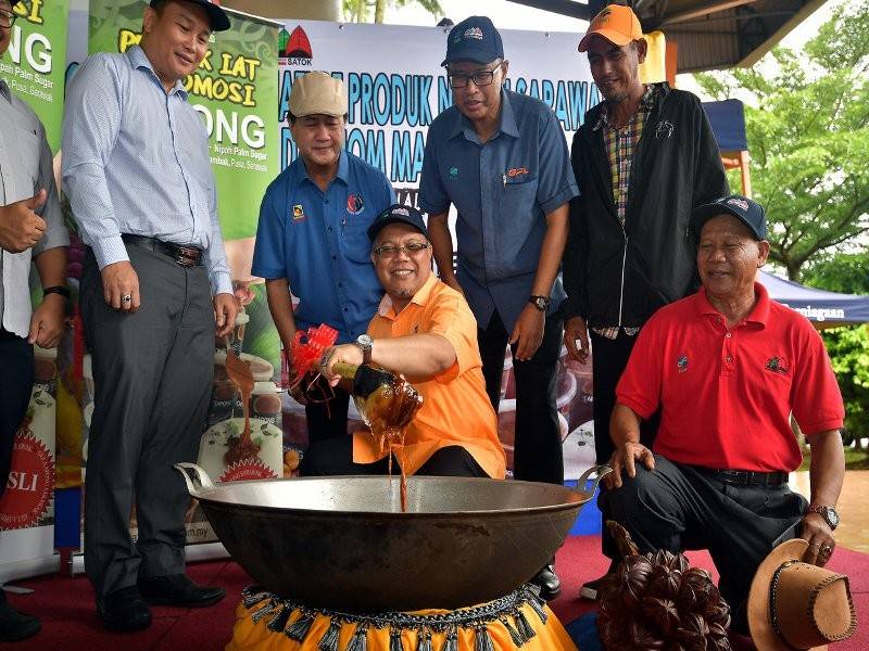 Pengerusi Lembaga Pemasaran Pertanian Persekutuan (Fama) Ishak Ismail (tengah) mengacau gula Apong sebagai gimik pelancaran promosi gula Apong di Medan Niaga Satok hari ini.
Program itu bertujuan mempromosikan gula Apong sebagai &#039;signature&#039; produk negeri Sarawak keluaran usahawan tempatan. - Foto Bernama 