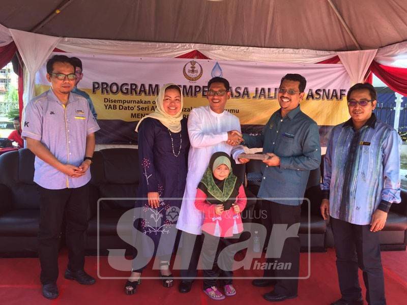 Ahmad Faizal (tengah) menyerahkan sumbangan zakat LAP untuk diagihkan kepada golongan asnaf pada Program Memperkasa Jalinan Asnaf di sini.