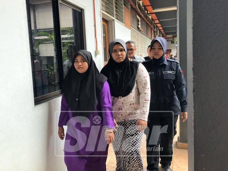 Nurul Ashiella (kiri) dan Nur Azhani dikawal polis keluar dari mahkamah selepas dituduh sebelum Azhani dibebaskan selepas jamin dijelaskan.
