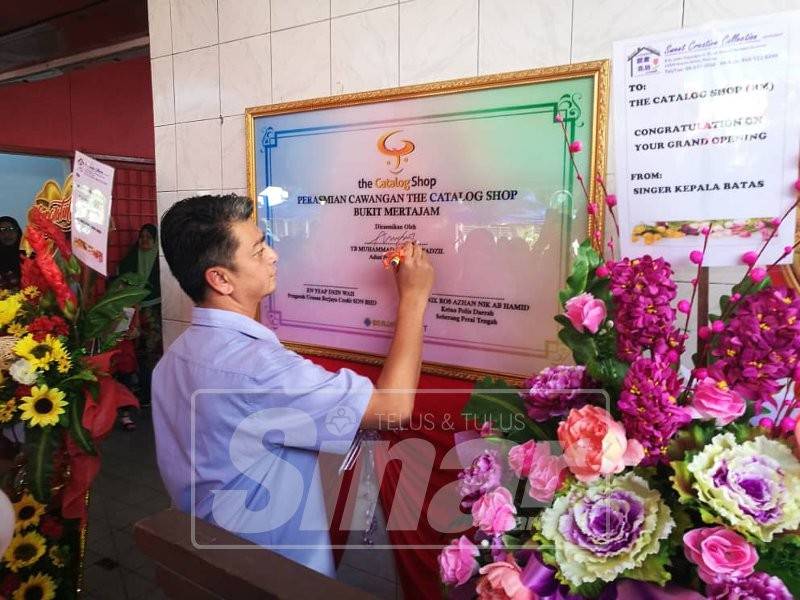 Faiz menandatangani plak perasmian dalam majlis pembukaan rasmi Kedai Catalog di sini, semalam.