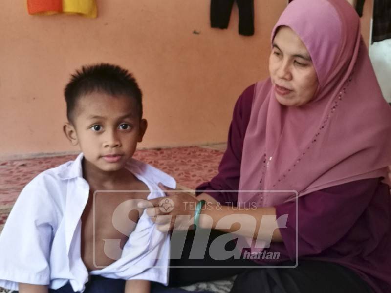 Zarina menunjukkan Chemo Port yang dipasang pada dada Nik Amin untuk rawatan penyakit leukimia yang dihadapi.