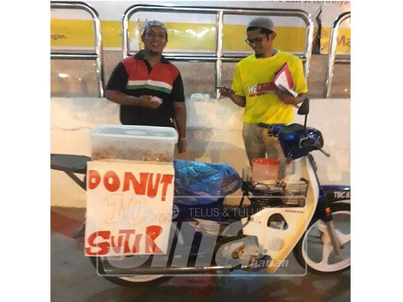  Idham Syafiq (kiri) bersama seorang pelanggan di sekitar bandar Kuala Terengganu.
